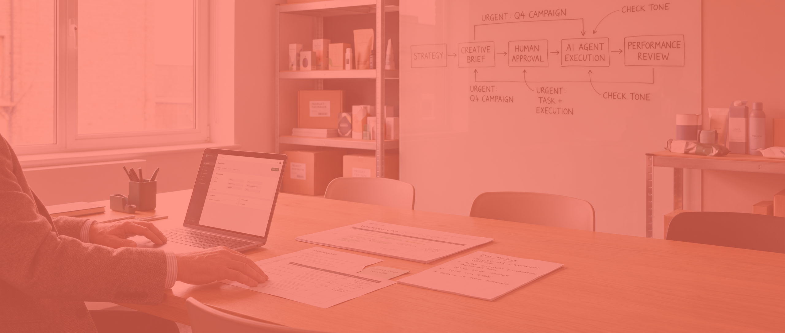 Human-directed planning session with annotated workflows and marketing materials in a modern commercial workspace with intensified coral brand overlay.