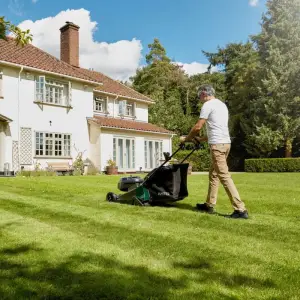 Mowing the lawn of a country house with a cordless mower